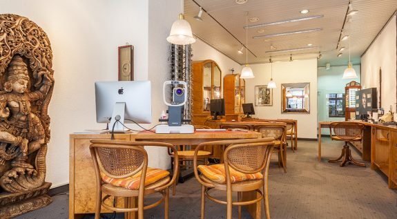 Heller Optikerladen mit moderner Messtechnik, Holzmöbeln und dekorativer Holzskulptur.